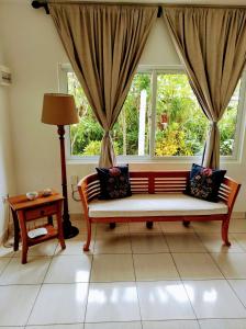 a living room with a bench in front of a window at Lucy's guesthouse in La Digue