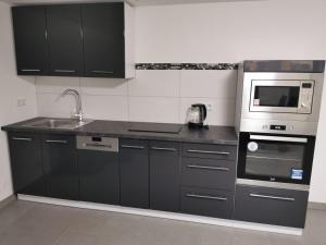 a kitchen with black cabinets and a sink and a microwave at Ferienwohnung Annashome in Maxhütte-Haidhof