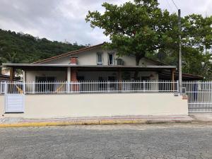 a white house with a fence in front of it at SUITE RUA PESCADA AMARELA in Bombinhas