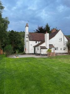 a large white house with a grass yard at 1 & 2 Foundry Cottages in Sutton Maddock