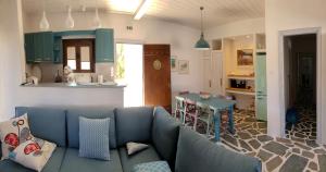 a living room with a blue couch and a kitchen at Dendrinos House in Galissas