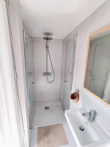 La salle de bains blanche est pourvue d'une douche et d'un lavabo. dans l'établissement BoHouse apartment No1, à Preila