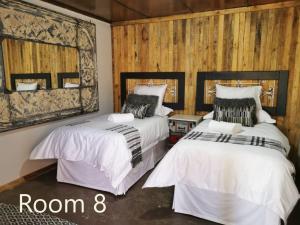 Kromdraai Guest Rooms في Kromdraai: سريرين في غرفة بجدران خشبية