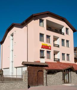 a large white building with a red sign on it at Aneli Hotel in Bansko