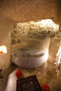 a bathroom with a tub in a stone room at Turkish Cave House in Ortahisar