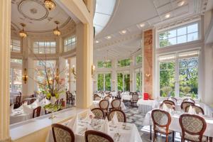 restauracja z białymi stołami, krzesłami i oknami w obiekcie Ensana Thermia Palace w Pieszczanach