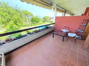 balcone con parete rossa, tavolo e sedie di appartamento con piscina Il glicine sul garda a Desenzano del Garda