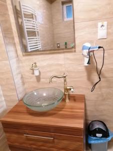 ein Badezimmer mit einem Glaswaschbecken auf einer Holztheke in der Unterkunft ZOLDAV in Nyíradony