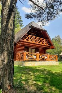 une cabane en rondins avec une clôture et un arbre dans l'établissement Zlatiborske brvnare, à Zlatibor