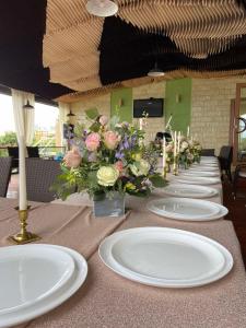un lungo tavolo con piatti bianchi e fiori di Villa Lavanda a Vapniarca