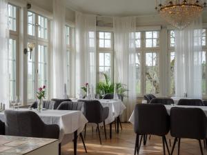 uma sala de jantar com mesas, cadeiras e janelas em Johannesbergs Slott em Rimbo