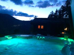 - une piscine avec une maison la nuit dans l'établissement Atelier Berg zum Bildji, à Staldenried