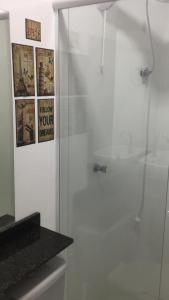a shower stall in a bathroom with posters on the wall at Flat Santa Cruz do Sul in Santa Cruz do Sul