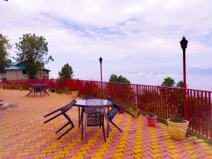 eine Terrasse mit einem Tisch, Stühlen und einem Zaun in der Unterkunft Hotel Himdhara, Dalhousie in Dalhousie