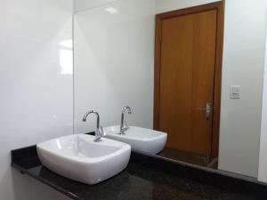 a bathroom with two white sinks and a mirror at Flat Santa Cruz do Sul in Santa Cruz do Sul