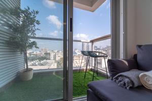 Una sala de estar con un sofá y una ventana grande. en PORT CITY HAIFA - German Colony Luxurious 2 bdrms Apt - MAMAD, en Haifa