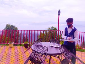 um homem de máscara segurando um prato numa mesa em Hotel Himdhara, Dalhousie em Dalhousie