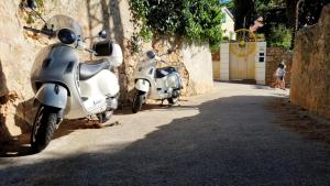 zwei Motorroller, die neben einer Mauer auf einer Straße geparkt sind in der Unterkunft Apartments Veli Lošinj in Veli Lošinj