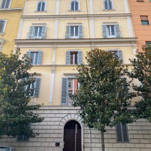 un grand bâtiment jaune avec une porte et des arbres dans l'établissement Inn Urbe Colosseo, à Rome