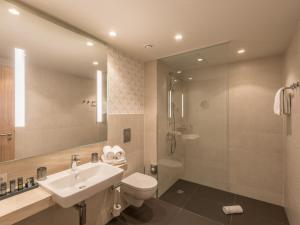 ein Bad mit einem Waschbecken, einem WC und einer Dusche in der Unterkunft Holiday Inn - Hamburg - Berliner Tor, an IHG Hotel in Hamburg