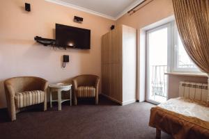 a room with a bed and two chairs and a television at Ekaterina II Hotel in Odesa