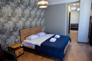 een slaapkamer met een groot bed en een blauwe deken bij Tskaltubo Epic Hotel & Spa in Tskaltubo