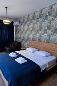 een slaapkamer met een groot bed en een blauwe deken bij Tskaltubo Epic Hotel & Spa in Tskaltubo