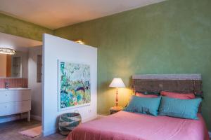 a bedroom with a bed and a green wall at Le Rucher des Arts in Alba-la-Romaine