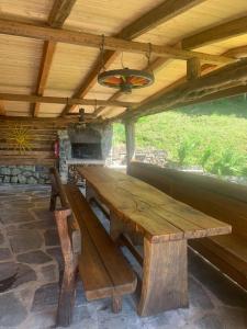 una gran mesa de picnic de madera bajo un techo de madera en DOSSENA Splendido Chalet di Montagna immerso nella natura, en Madonna della Costa