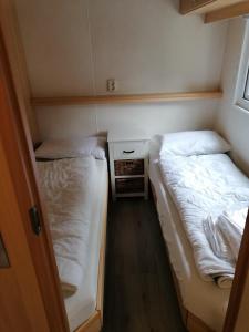 een kleine kamer met 2 bedden en een nachtkastje bij Chalet 4-6 Personen Epe F15 Van alle gemakken voorzien Max aantal volwassen personen bedraagt 4 in Epe