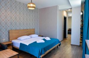 een slaapkamer met een groot bed met blauwe lakens en witte kussens bij Tskaltubo Epic Hotel & Spa in Tskaltubo