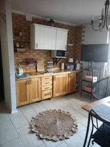 a kitchen with wooden cabinets and a rug on the floor at Apartament Maki Apartament na wyłączność in Krynica Morska