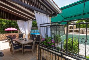 a patio with a table and chairs and a fence at Apartment With A Private Swimming Pool, Garden & BBQ in Gostinjac