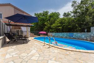 a swimming pool with an umbrella next to a house at Apartment With A Private Swimming Pool, Garden & BBQ in Gostinjac