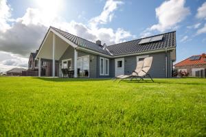 a house with a lawn and two chairs in the yard at Wangermeer - Ferienhaus in Wangerland