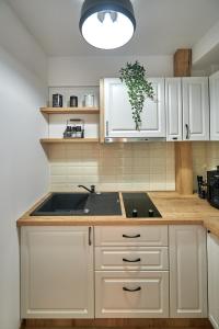a kitchen with white cabinets and a sink at Romantic Studio in Braşov