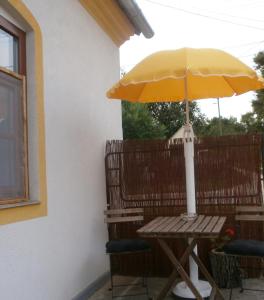 a table with a yellow umbrella on a patio at Ninszianna Apartman in Hegyhátszentjakab