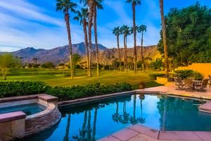 una piscina con palmeras y un campo de golf en Escape to Luxury at PGA West Permit# 67092, en La Quinta