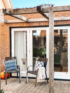 un patio al aire libre con 2 sillas y una pérgola en Vakantiewoning Domburg DO34, en Domburg