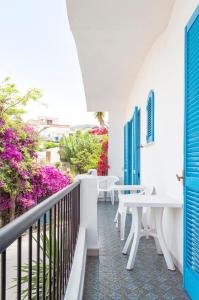 un balcone con tavoli bianchi e fiori viola di Hotel la Maggioressa a Ischia