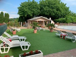 a lawn with white chairs and tables on it at Mediterán Fedett Medencés Apartmanház in Szántód