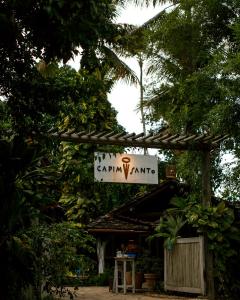 a street sign on a pole in front of a palm tree at Pousada Capim Santo in Trancoso