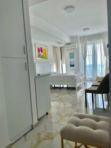 a white living room with a bed and a dining room at Studio Crazy Beach Summerland in Mamaia