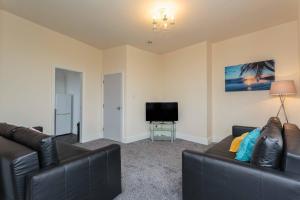 a living room with two leather couches and a television at Cherry Property - Mango Suite in Blackpool