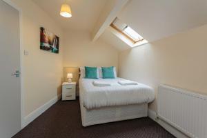 a bedroom with a bed with blue pillows and a window at Cherry Property - Mango Suite in Blackpool