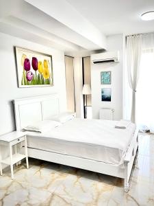 a white bedroom with a white bed and flowers on the wall at Studio Crazy Beach Summerland in Mamaia