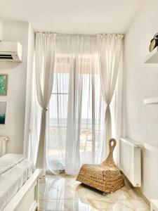 a bedroom with a large window with white curtains at Studio Crazy Beach Summerland in Mamaia