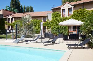 a pool with chairs and umbrellas next to a building at Logis Des Trois Massifs in Claix