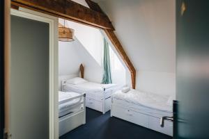 Les Chouettes Hostel في رين: غرفة صغيرة بسريرين ومرآة