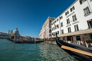 a canal with two gondolas in the water next to buildings at Monaco & Grand Canal in Venice